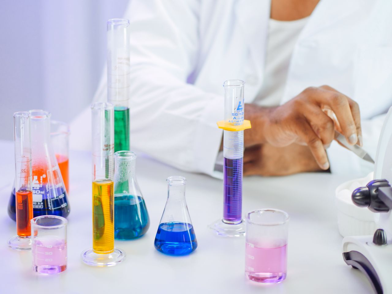 Services 4 A scientists hand working with colorful liquids in a laboratory setting.